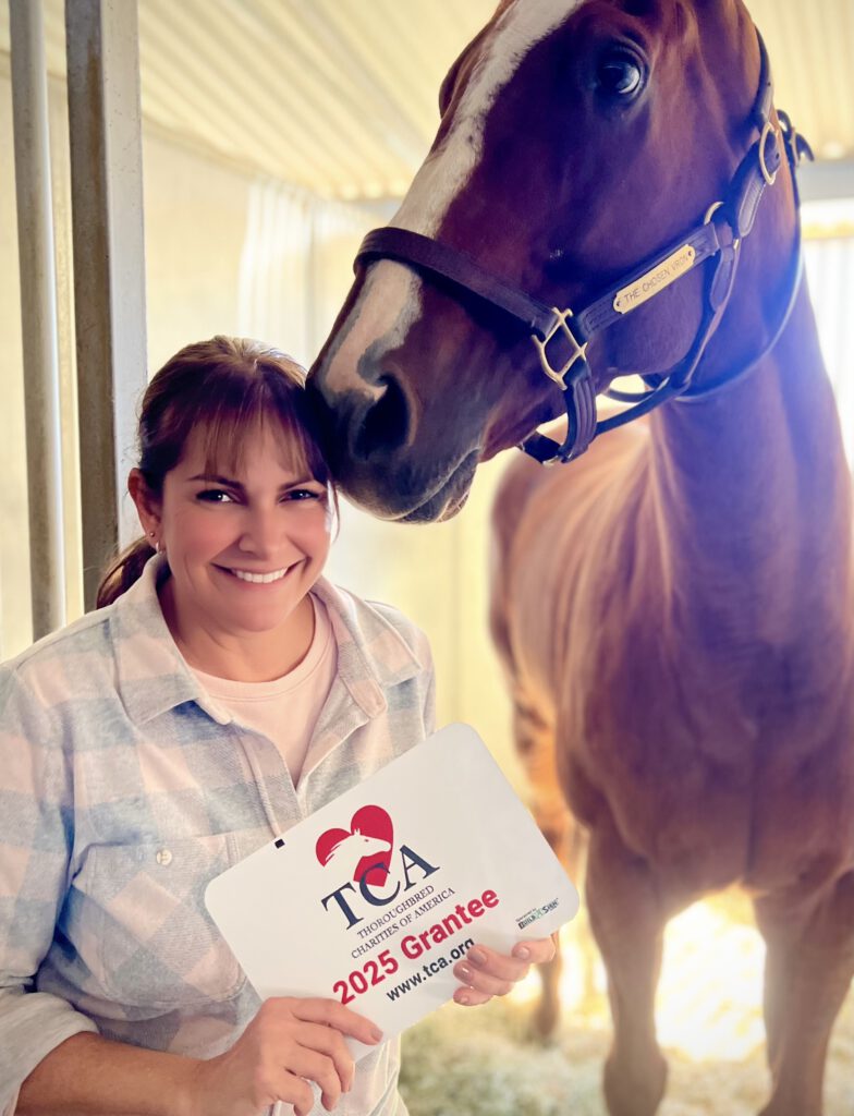 Katie Fisher owner of Kingfisher Farms holding the TCA Grantee sign and the Chosen Vron, a retired racehorse.